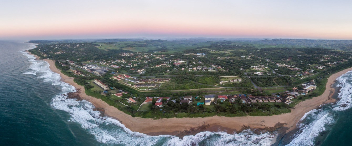 Aerial view of Hibberdene, its beaches and the green hills behind at sunrise